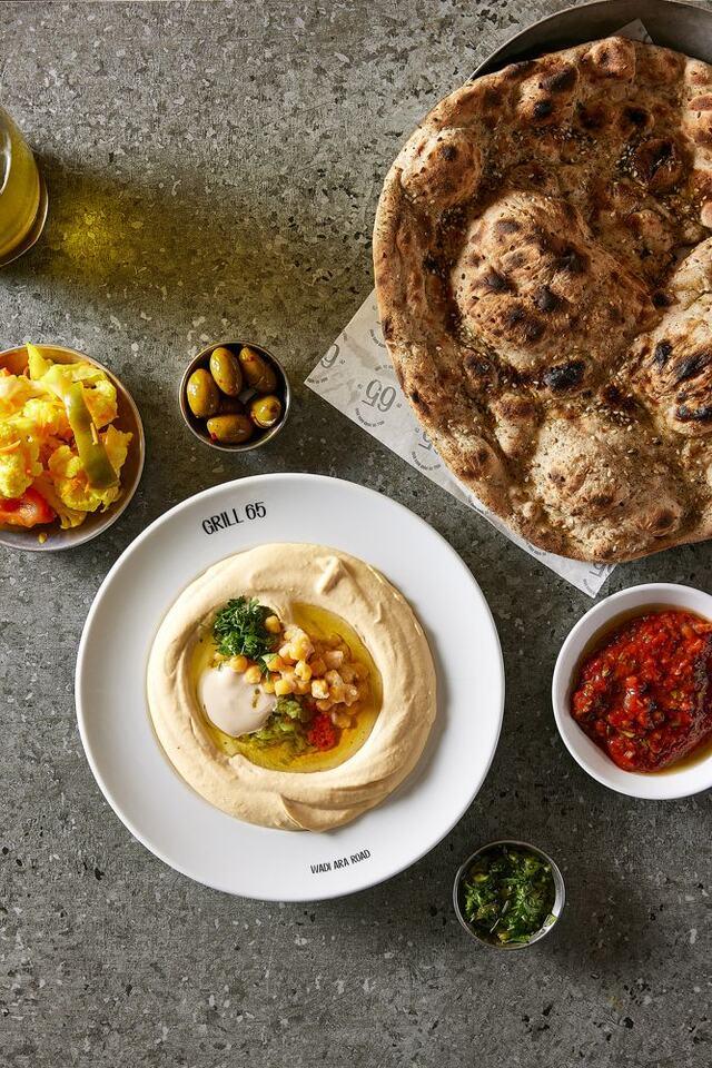 צלחת חומוס קרמית עם גרגירים חמים ושמן זית במרכז